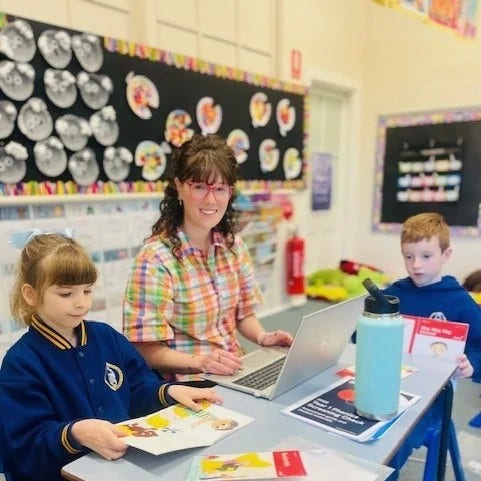 Teacher is supporting students with their reading.h students