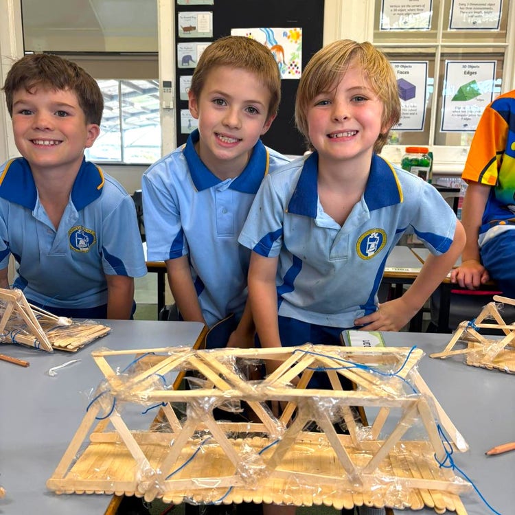 Three boys showing off their STEM bridge project