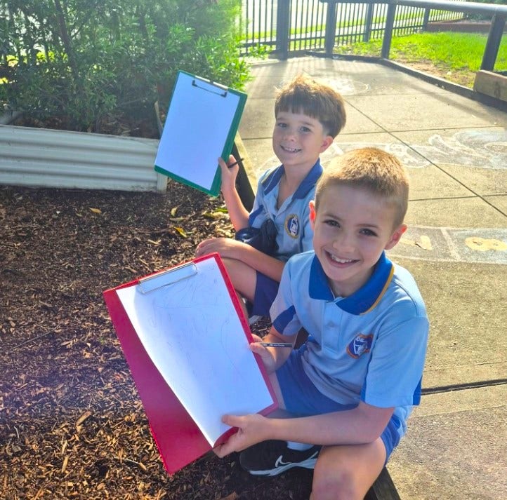 2 boys learning outside with clipboards