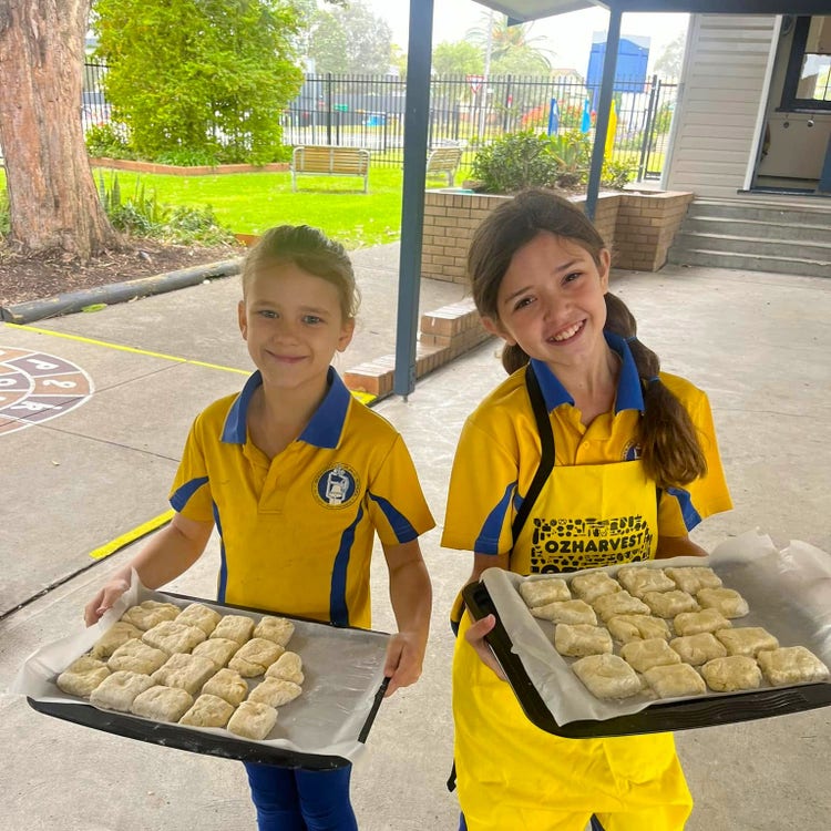 Two girls holding trays of johnny cakes they have cooked