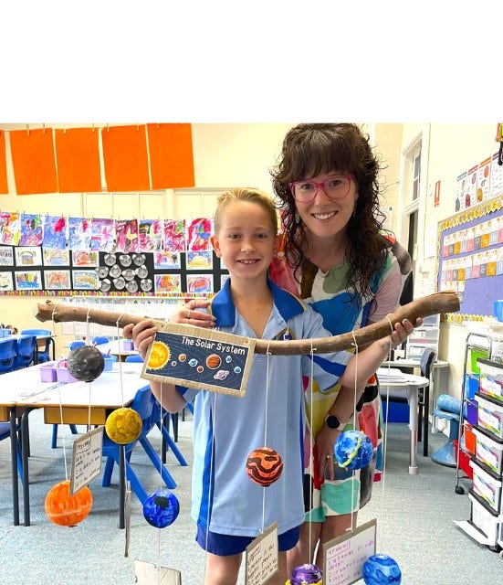 a teacher and students posing with a planet project the student created